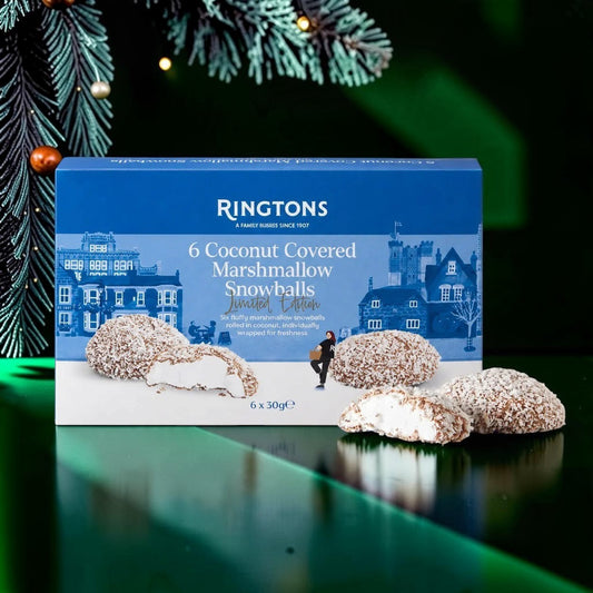 A box of Ringtons 6 Coconut Covered Marshmallow Snowballs Limited Edition alongside three individual snowballs, set against a festive dark green background with pine branches and warm lights.