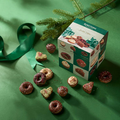 A Ringtons 'Juice for Love' chocolate box displayed on a green background with scattered miniature chocolate donuts and pastries.