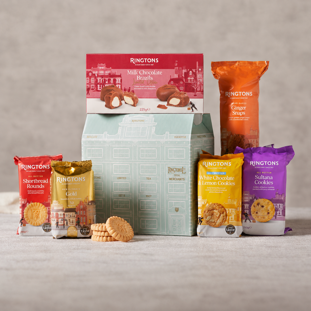 A Ringtons assorted biscuits gift set featuring multiple packaged cookies and a mint green gift box, arranged on a light gray surface against a neutral gray background.